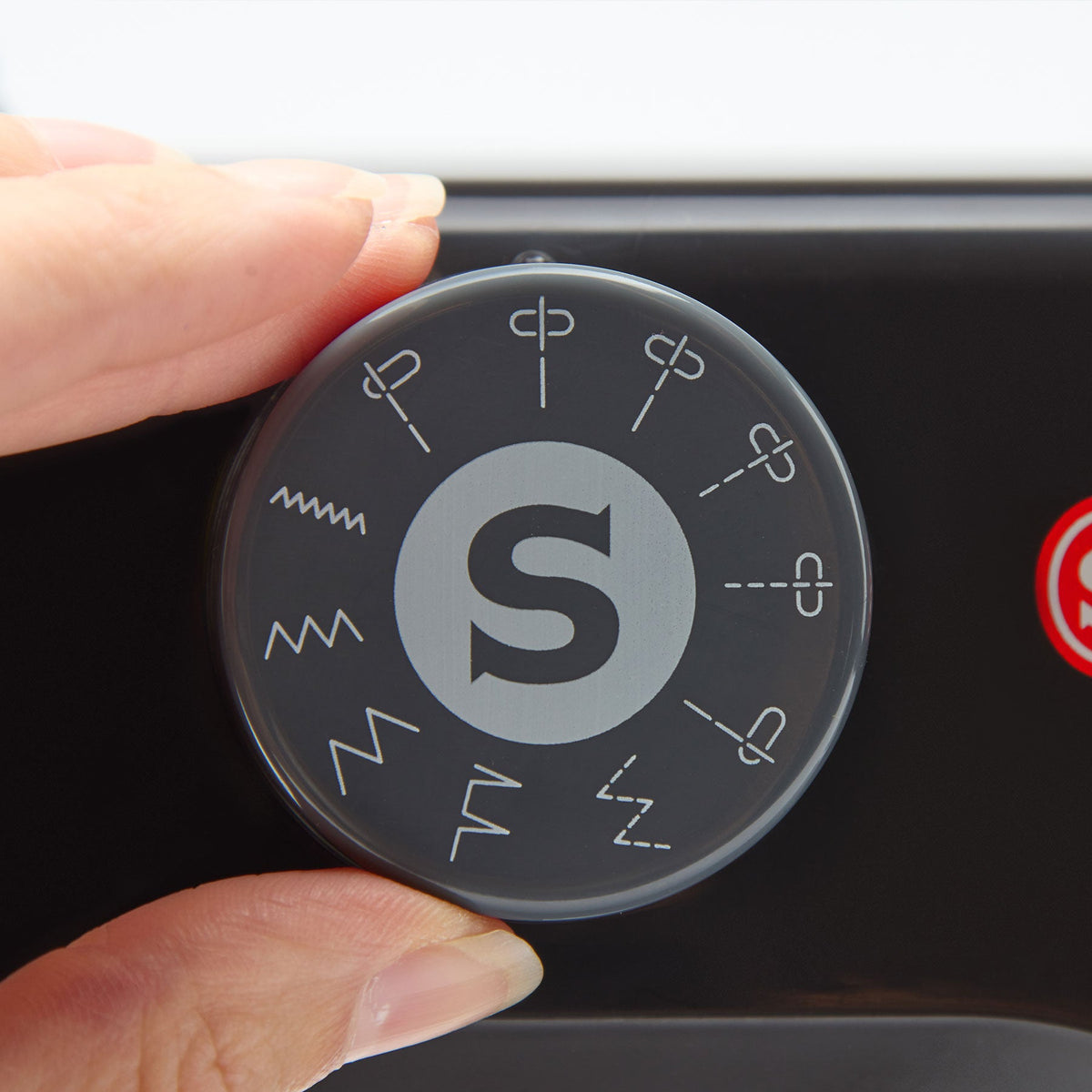 Hand turning the stitch selector dial on the Singer M1000 Black