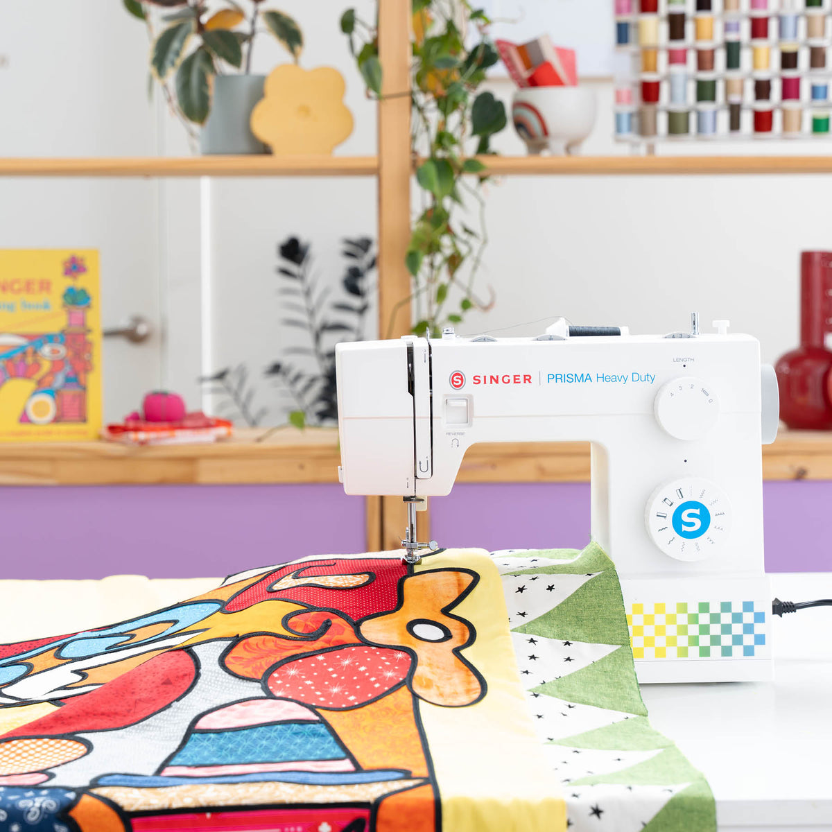 Singer Prisma Heavy Duty at a table with a large pieced quilt top beside the machine