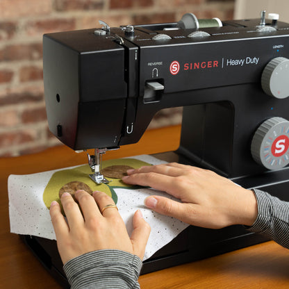 Singer Heavy Duty 4432 Black sewing machine with hands guiding fabric under the presser foot