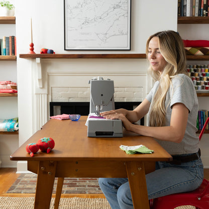 Woman sewing at a wooden table with the Singer Heavy Duty 6600C