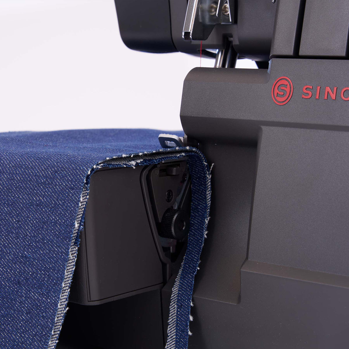 Singer HD0460 serger close-up with blue denim fabric draped over the front of the machine