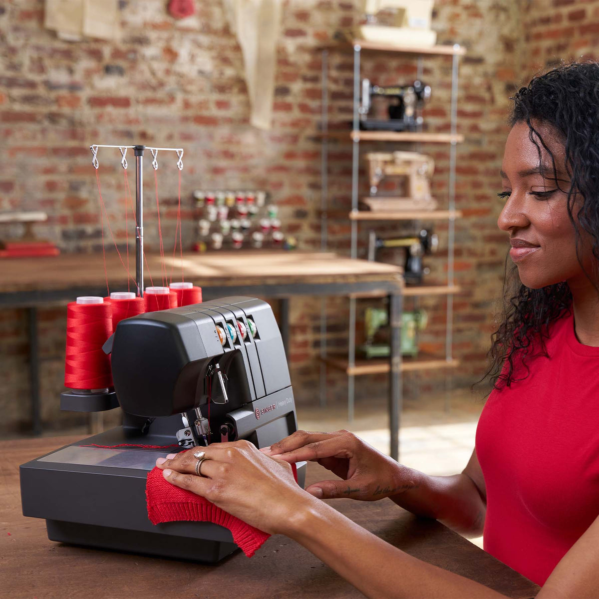 Woman smiling while feeding red knit fabric into a Singer HD0460 serger