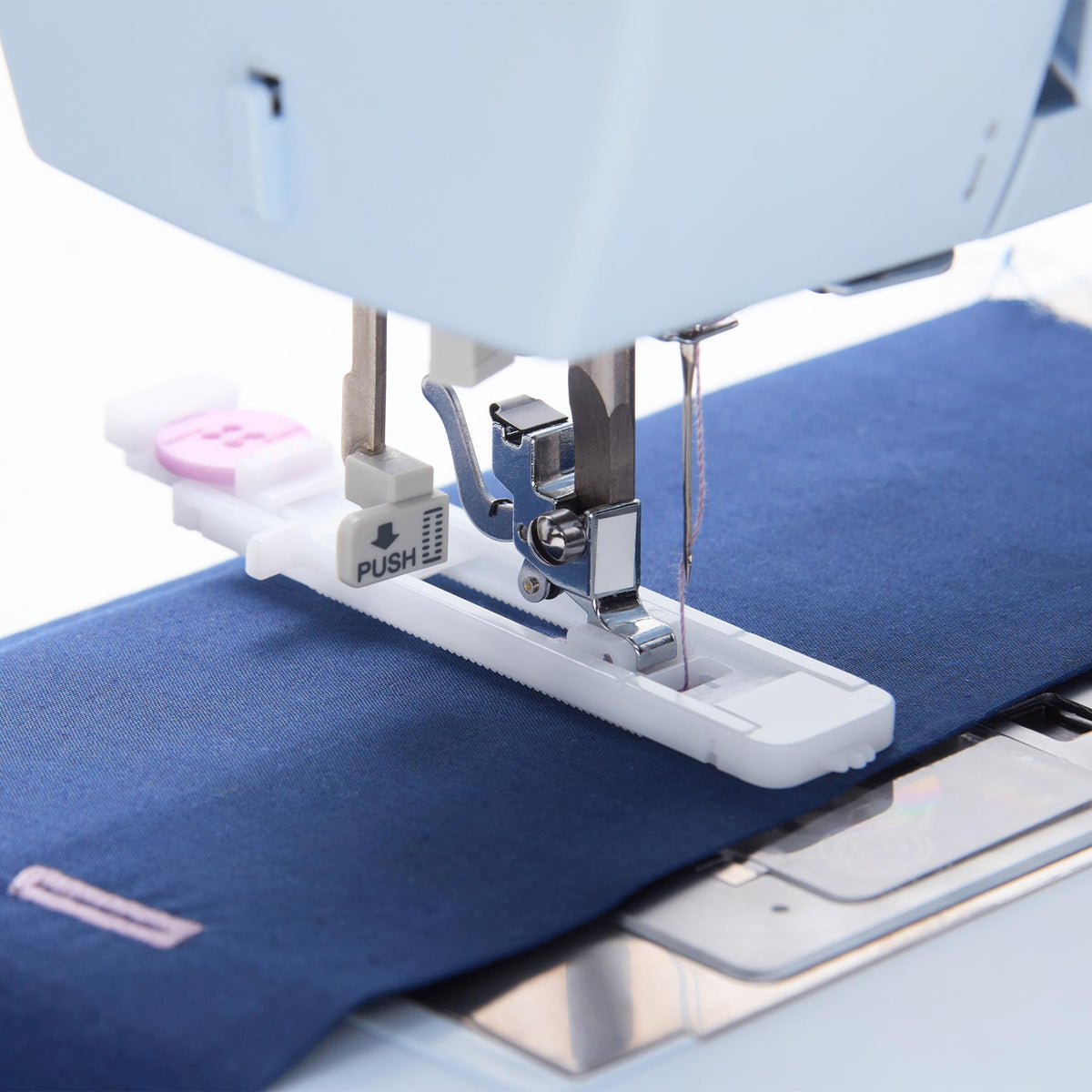 Singer Heavy Duty 4423 buttonhole foot holding a pink button on blue fabric