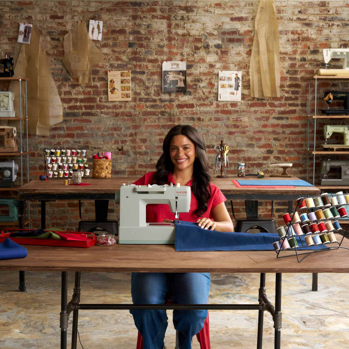 Woman seated at a sewing table with the Singer Heavy Duty 4511 Sage and spools of thread
