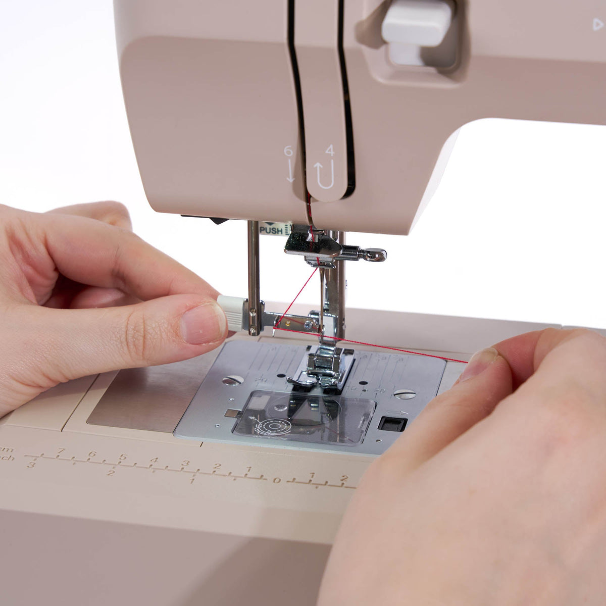 Hands guiding red thread to the needle of the Singer Heavy Duty 4523