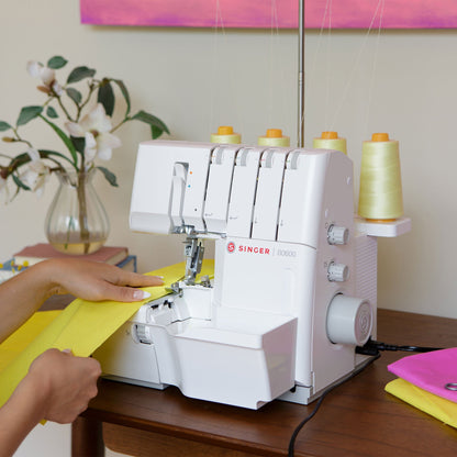 Singer S0600 serger in use with yellow fabric at a table