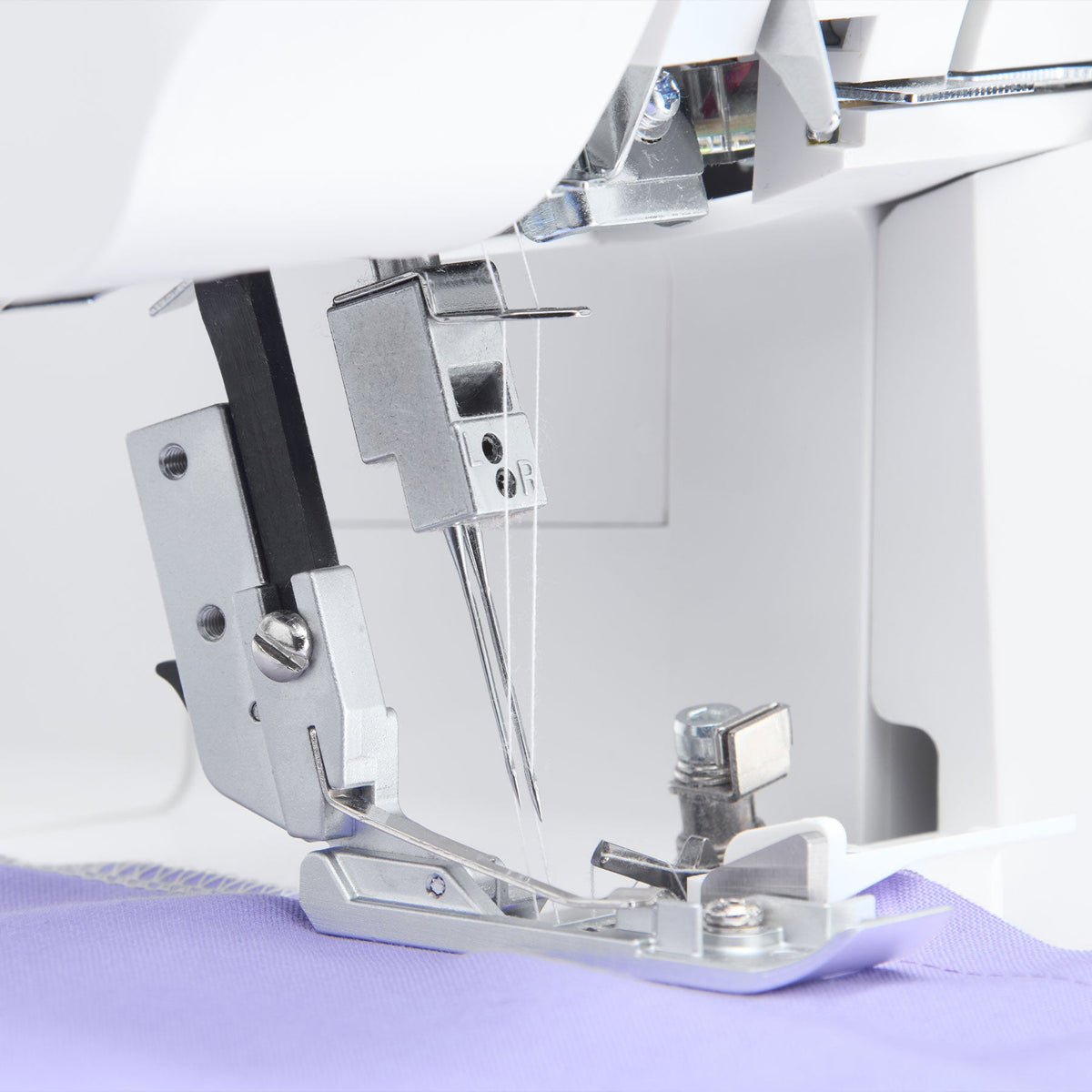 Singer S0600 serger needles and presser foot over purple fabric