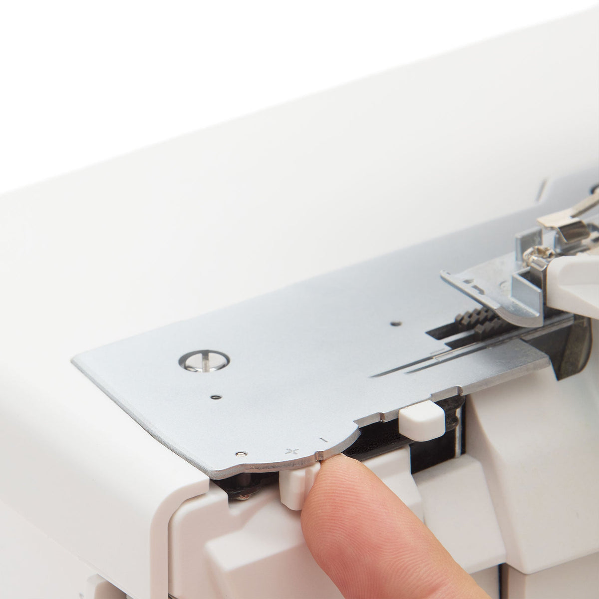 Singer S0600 serger needle plate with a finger on a lever beside the plate