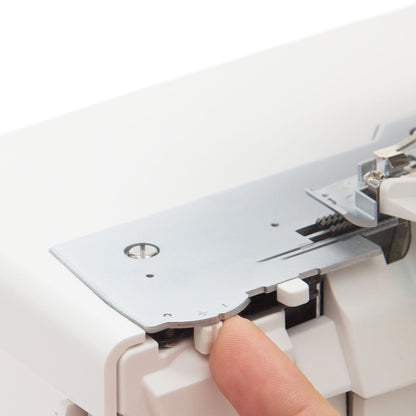 Singer S0600 serger needle plate with a finger on a lever beside the plate