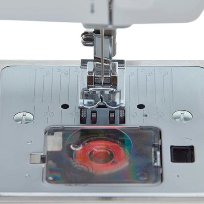 Singer Prisma Heavy Duty needle plate with the transparent bobbin cover over a red bobbin