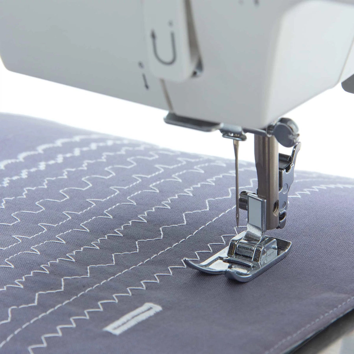 Singer Prisma Heavy Duty presser foot sewing zigzag stitch rows on gray fabric with a buttonhole outline